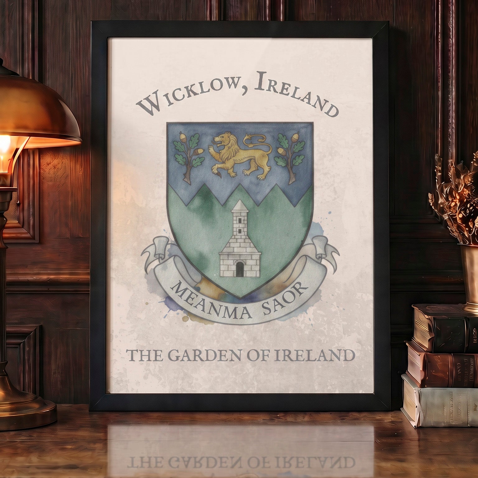 A framed art print featuring the Wicklow crest with the text 'Wicklow, Ireland' and 'Meanma Saor' and 'The Garden of Ireland', displayed on a wooden table in a cozy room setting with a lamp and books.